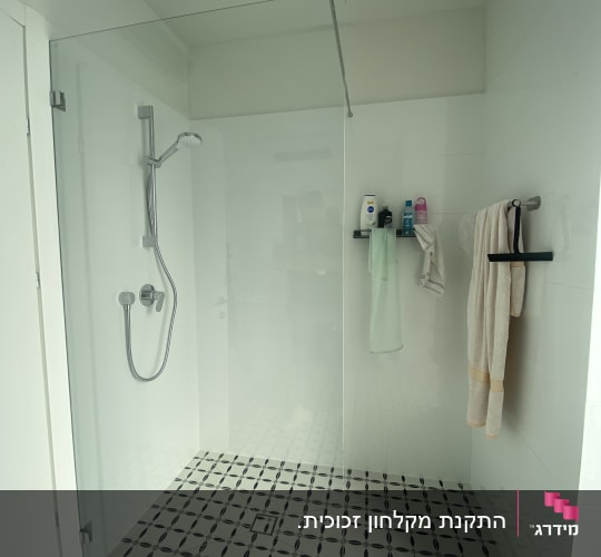 מקלחת עם ראש מקלחת, מגבות ומוצרי טיפוח על מדף